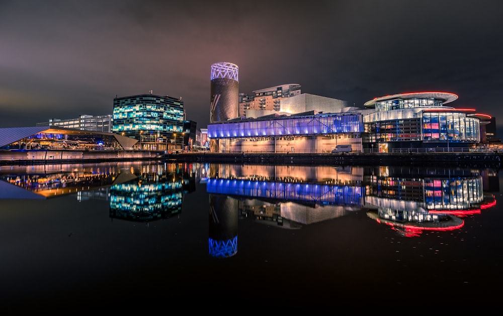 a night scene of a city with buildings and a body of water