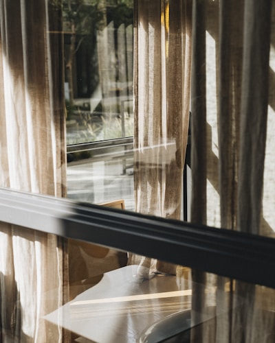 Soft morning light filtering through a restored Georgian sash window, highlighting delicate brass fittings and muted sage curtains.