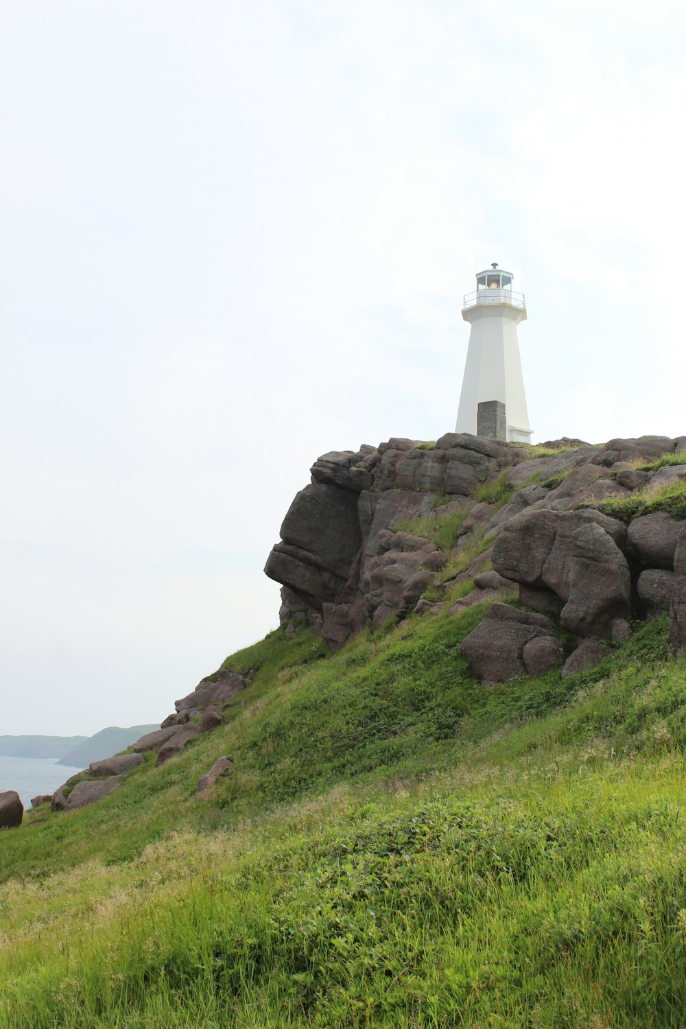 a lighthouse on top of a grassy hill