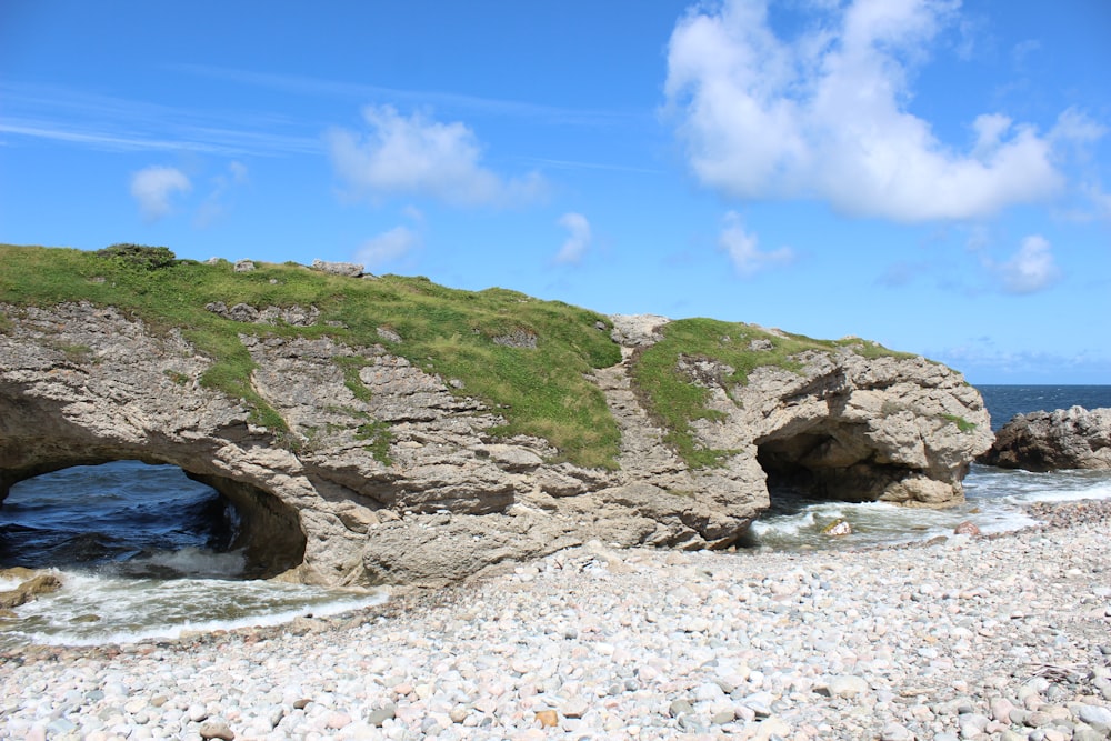 a rocky beach with a cave in the middle of it