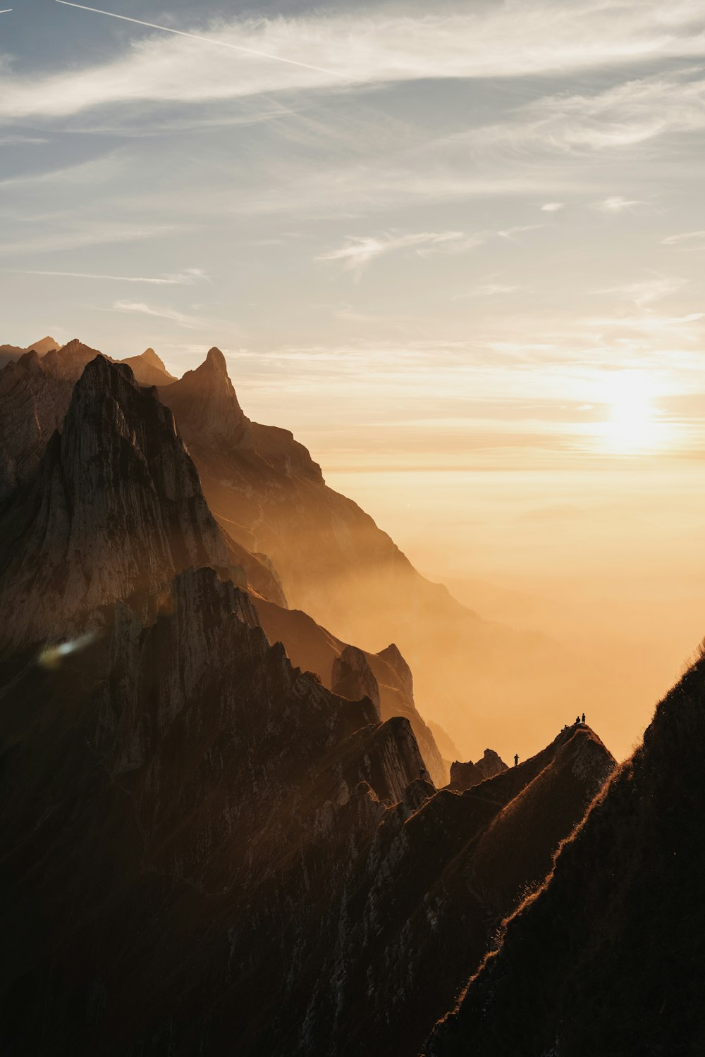 una persona in piedi sulla cima di una montagna al tramonto