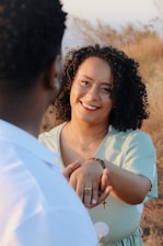 A woman smiling warmly as she holds hands with a supporter in a sunlit community center.