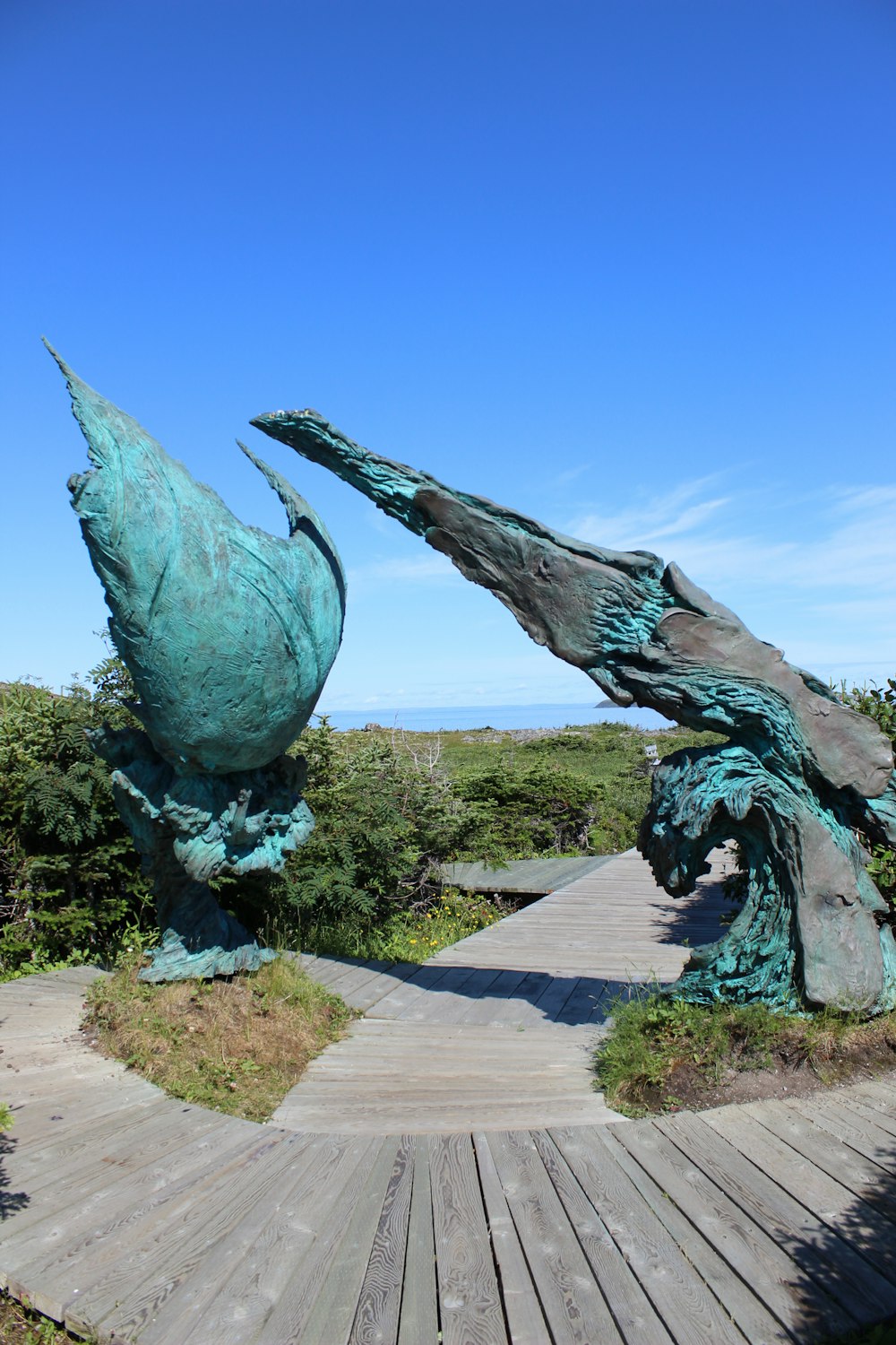 a statue of two birds on a wooden walkway