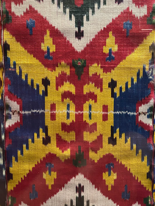 A vibrant hand-painted t-shirt featuring Aztec symbols in bold colors.