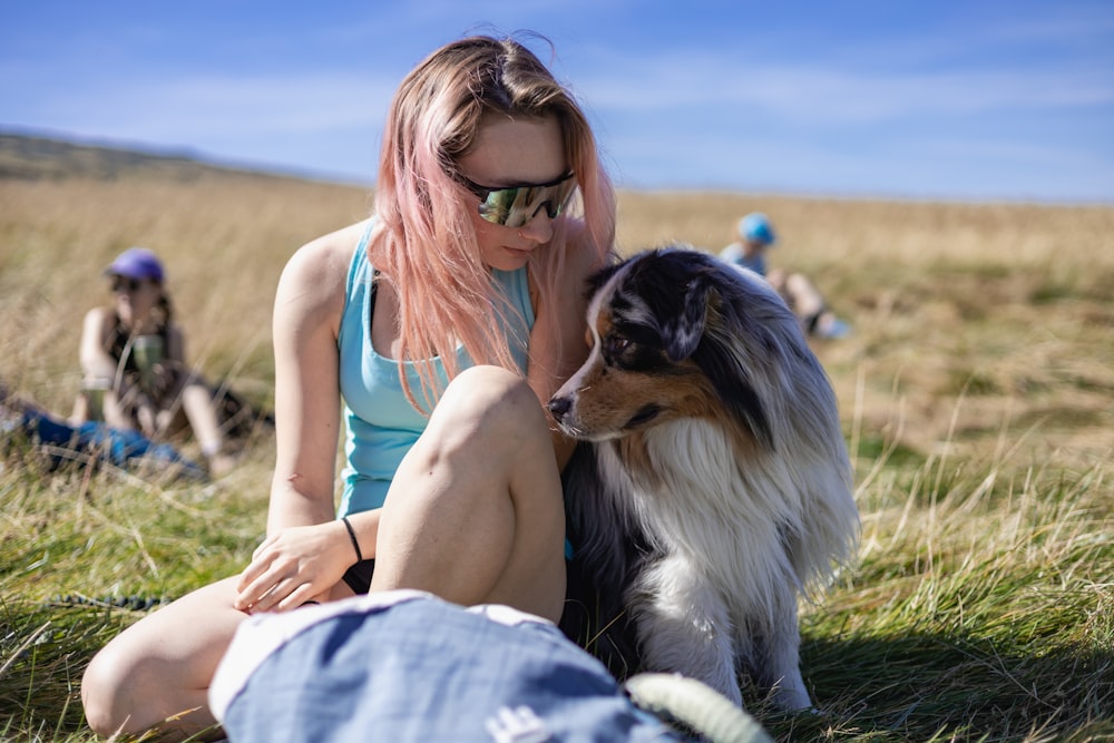 a woman sitting on the ground petting a dog