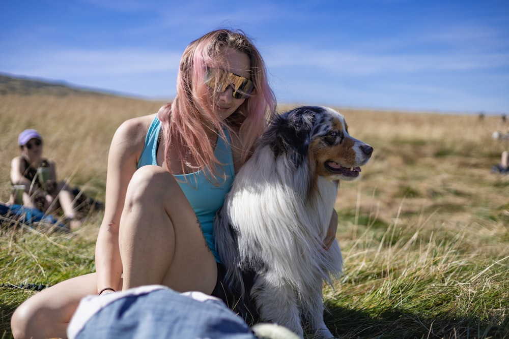 a woman with pink hair sitting next to a dog