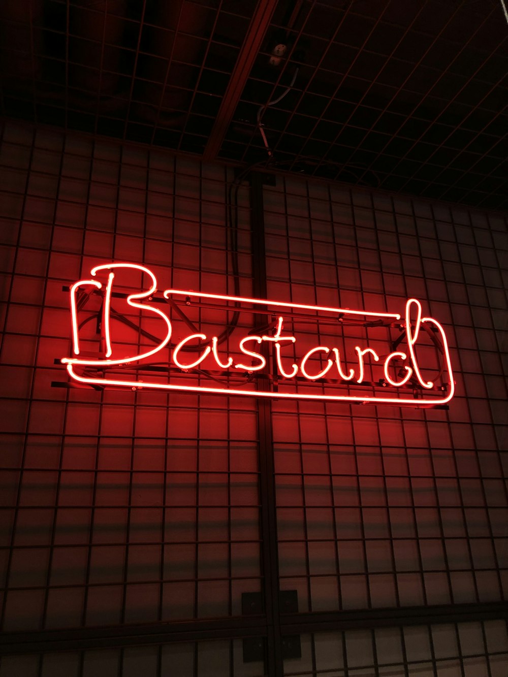 a red neon sign that reads bastard