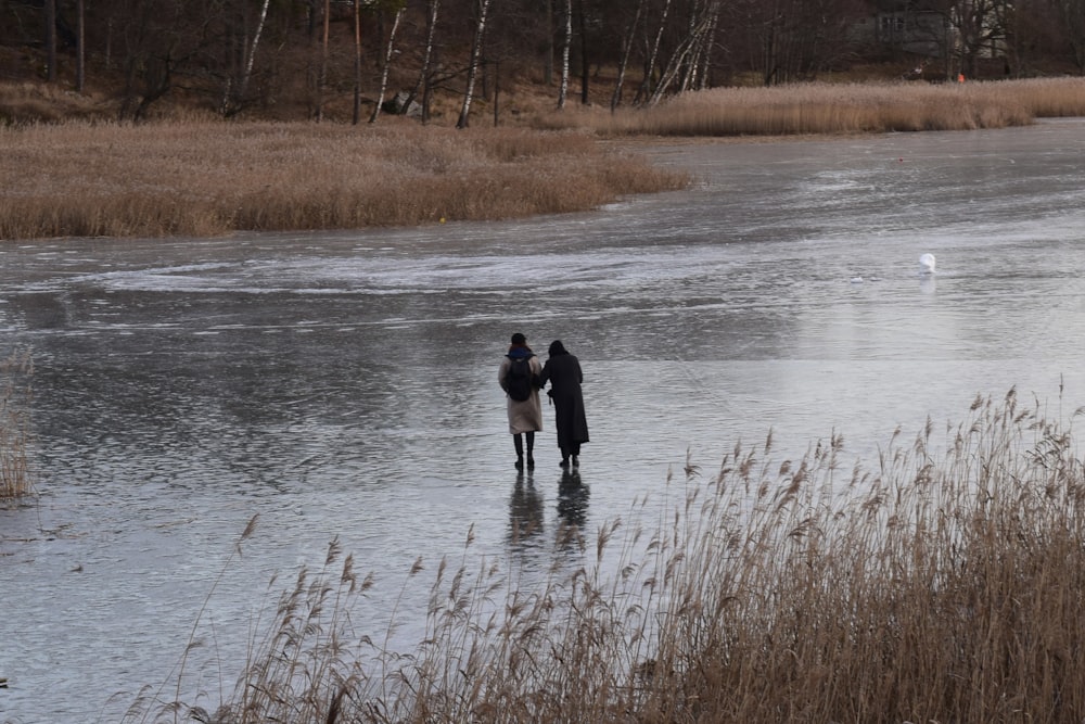 a couple of people standing in a body of water