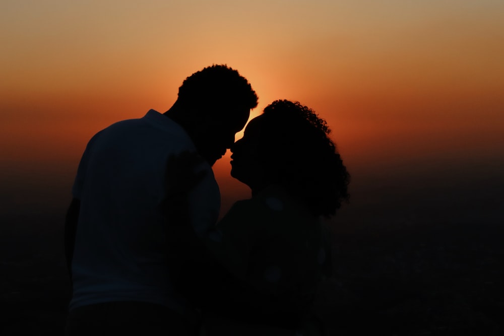 a silhouette of a man and a woman at sunset