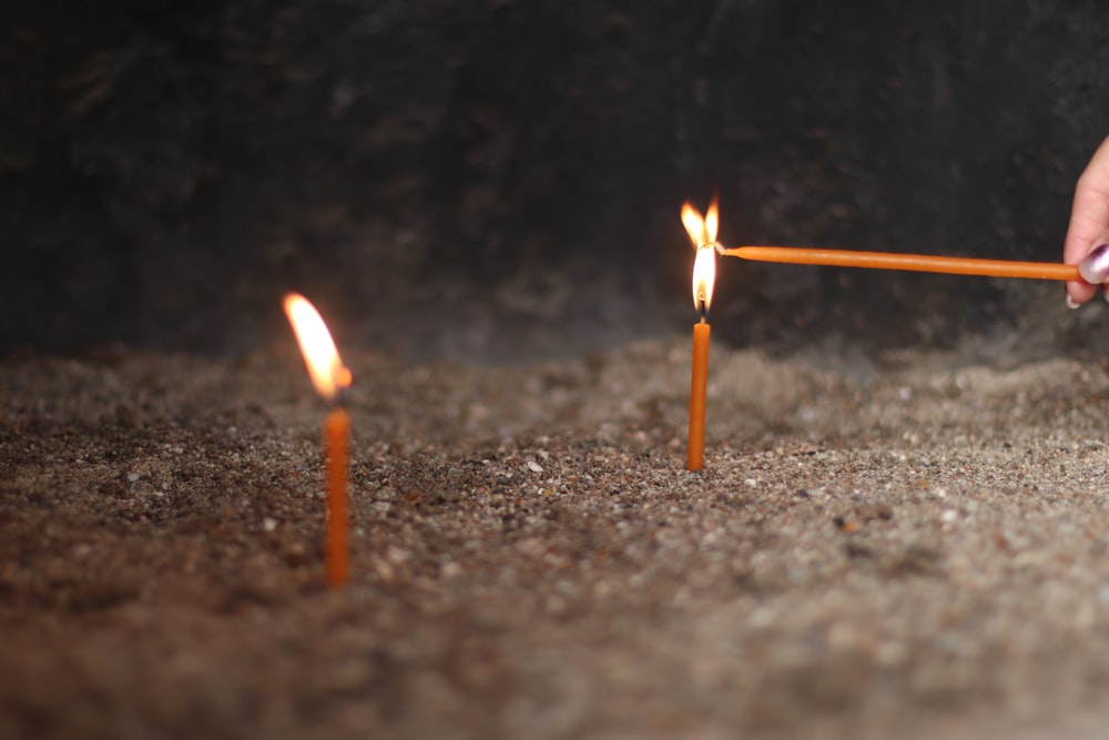 a person lighting a candle with a stick
