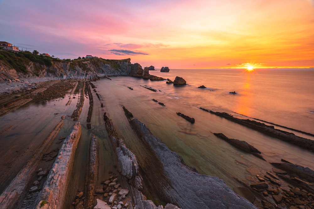 the sun is setting over a rocky beach