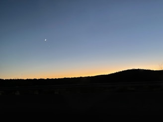 A serene sunset behind a silhouette of an astrologer studying ancient star charts.