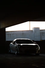 Sleek silver sports car silhouette against a dark, moody urban backdrop at night.