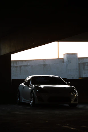 Sleek silver sports car silhouette against a dark, moody urban backdrop at night.
