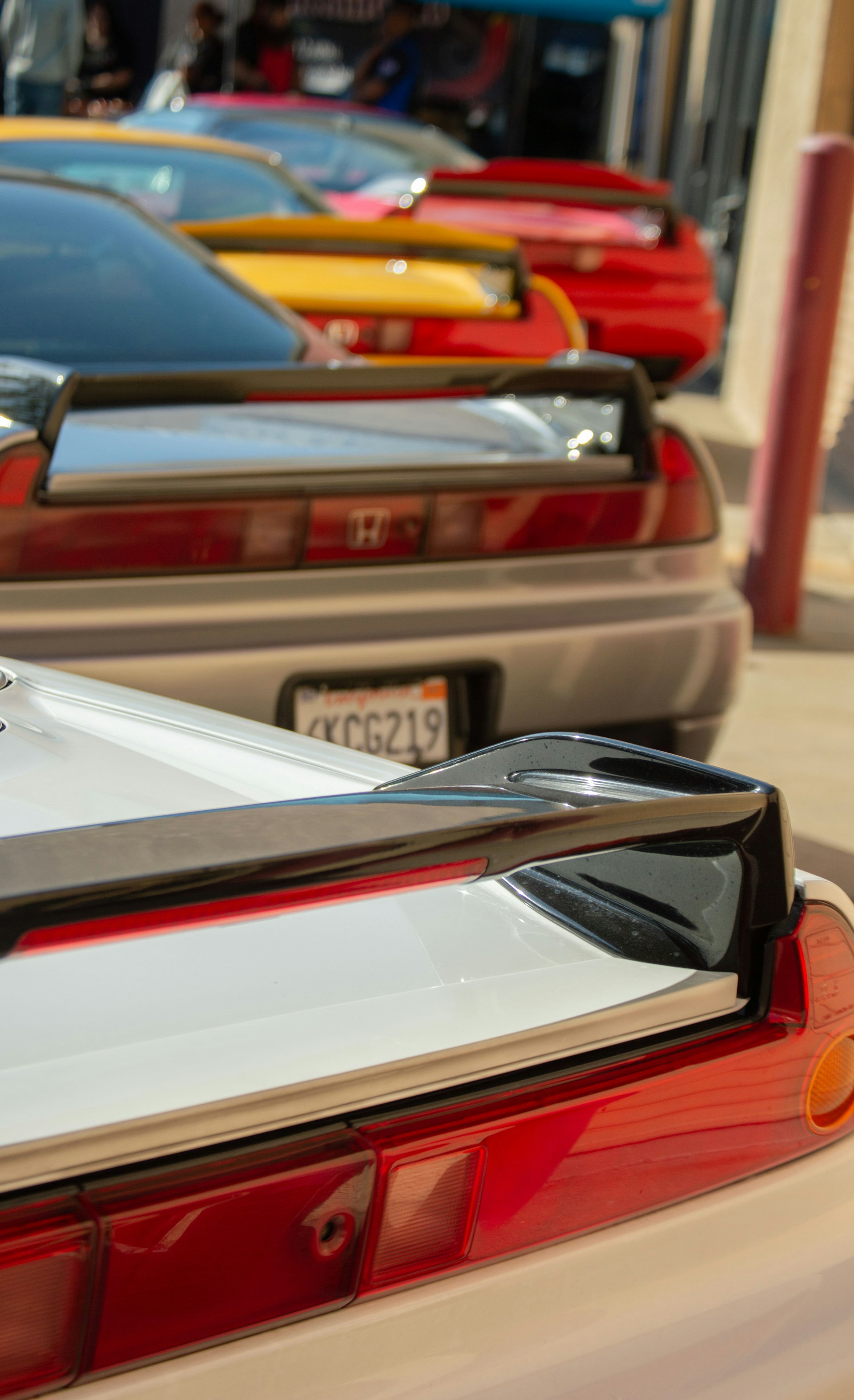 A lineup of cars in various colors and finishes wrapped with hentair films, displayed under bright showroom lights in Shenzhen.