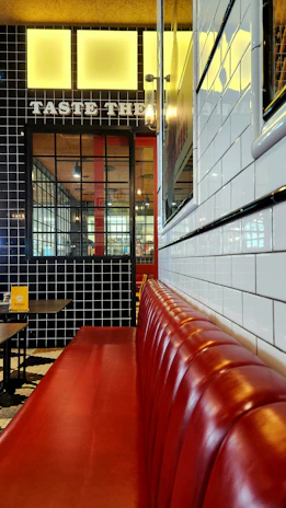 A sleek, modern restaurant booth with dark wood and plush red upholstery under warm lighting.