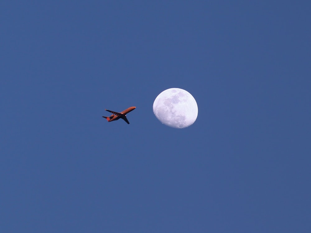Un aeroplano che vola nel cielo con la luna sullo sfondo