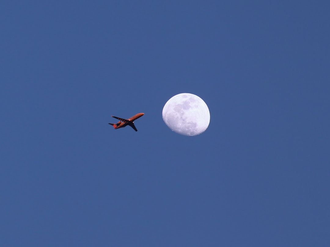 an airplane flying in the sky with the moon in the background, Actual photograph of a jetliner flying directly in front 