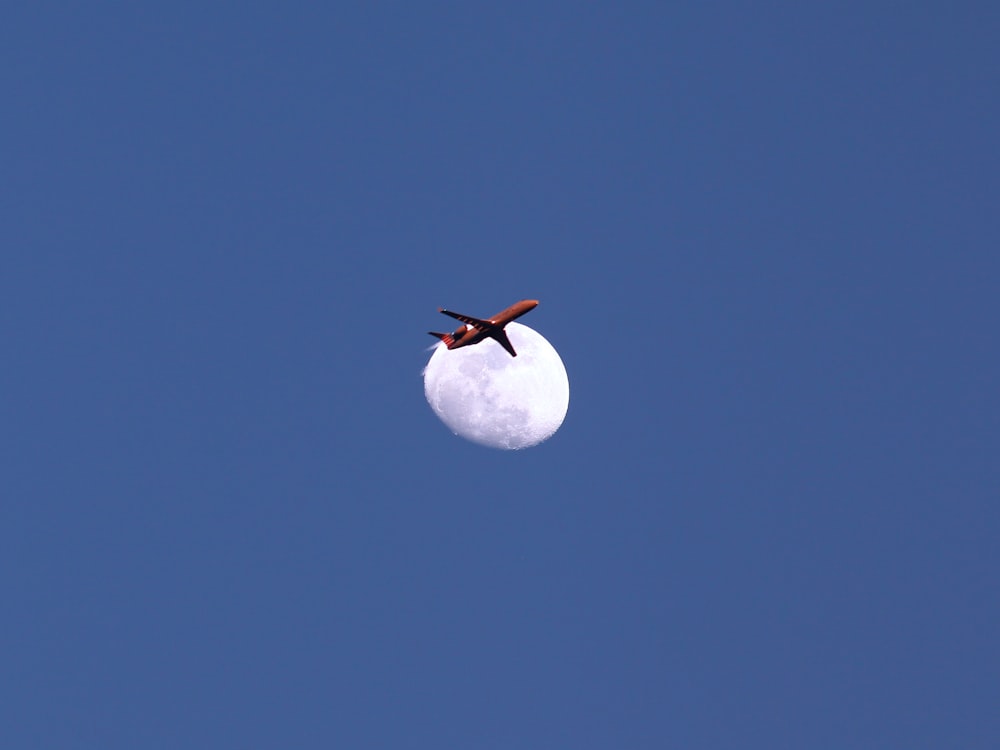 Un aeroplano che vola nel cielo con la luna sullo sfondo