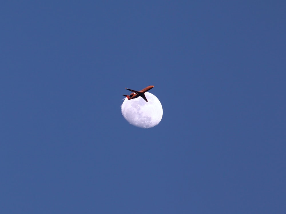 an airplane flying in the sky with the moon in the background