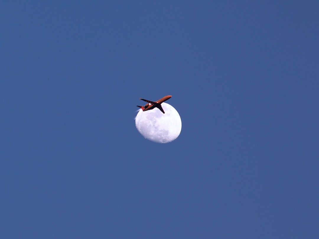 an airplane flying in the sky with the moon in the background, Actual photograph of a jetliner flying directly in front 