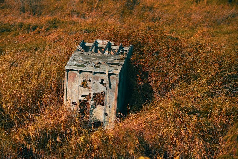 an old outhouse sitting in a field of tall grass