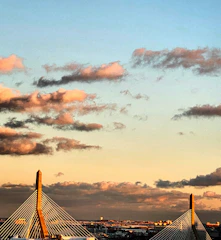 A sweeping view of a newly completed cable-stayed bridge spanning a vibrant city skyline at sunset