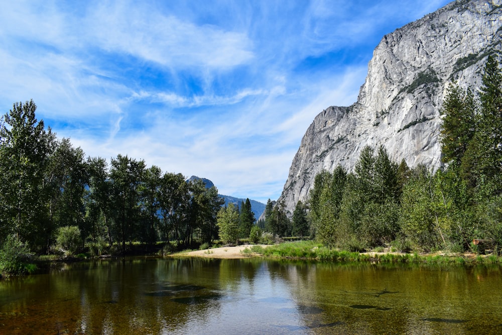 a river surrounded by trees and mountains under a blue sky