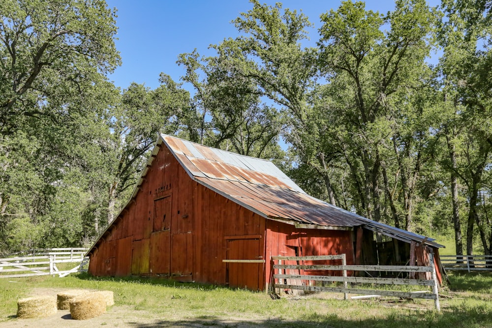 um celeiro vermelho com um telhado de metal em um campo