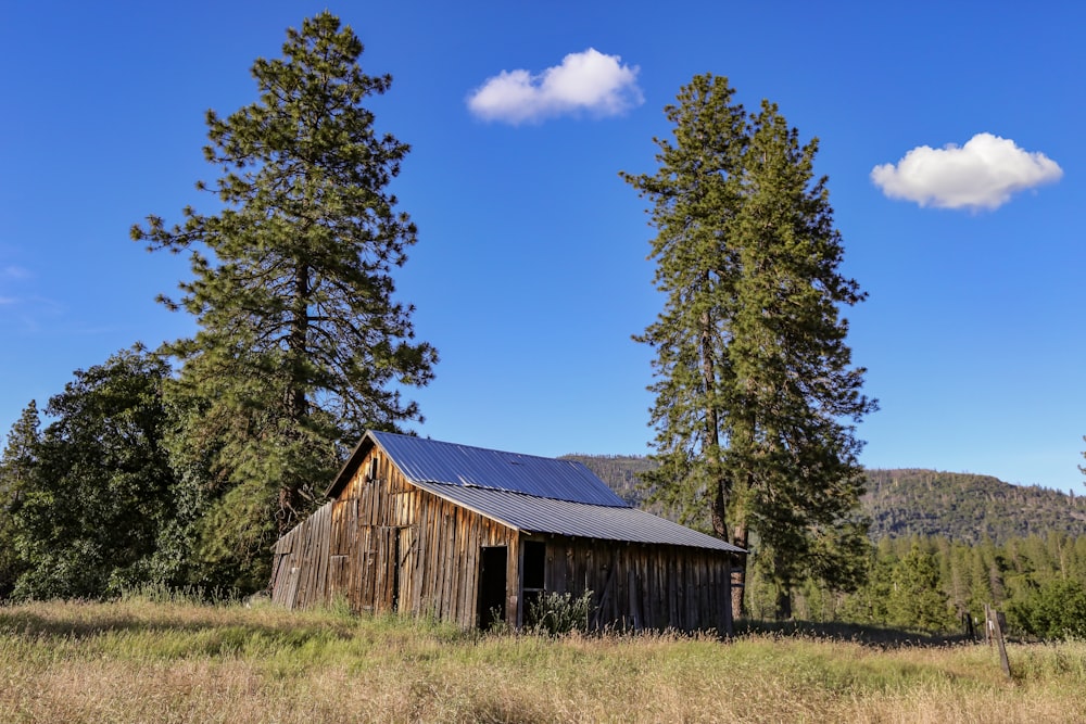 a barn in the middle of a field with trees in the background