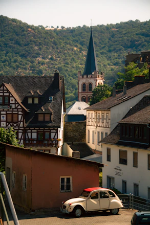 2D illustration of a cheerful village scene with people sharing a colorful car under a bright sky.