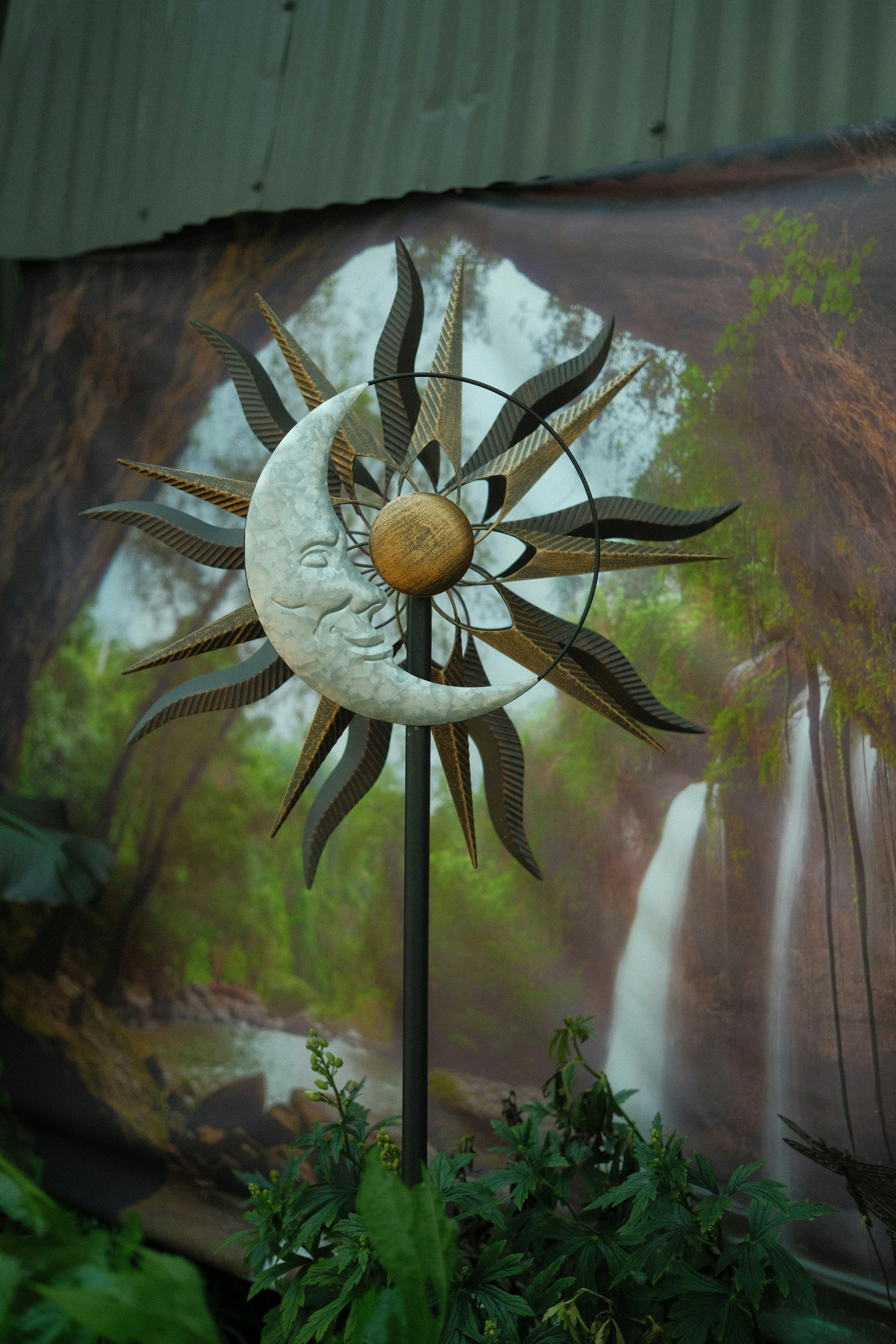 a metal sun and moon decoration in front of a painting