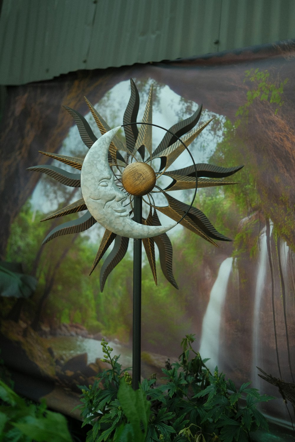 a metal sun and moon decoration in front of a painting