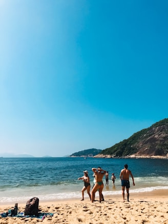 A sunlit beach scene with a diverse group of friends wearing vibrant summer outfits from Beach Life, laughing and walking along the shore.