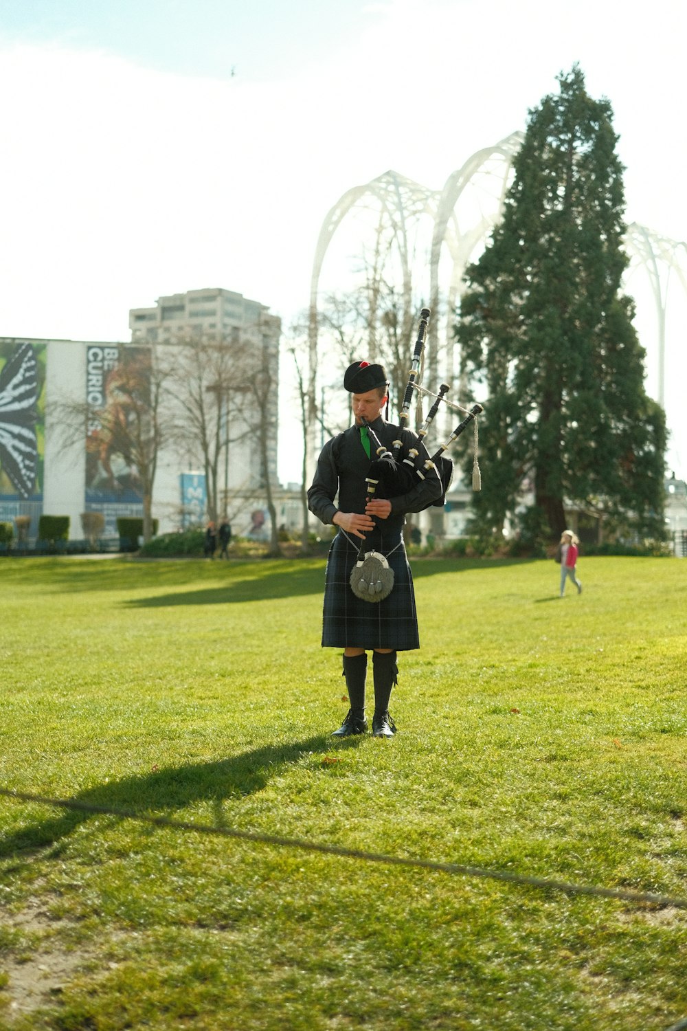 a man in a kilt playing bagpipes in a park