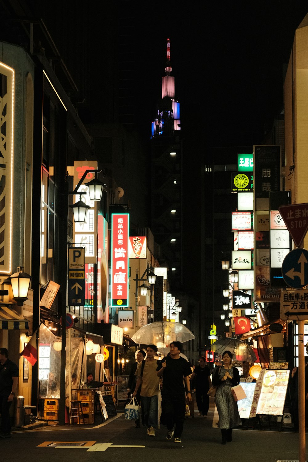 a group of people walking down a street at night