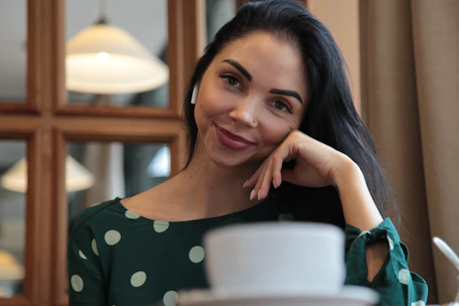 a woman sitting at a table with a cup of coffee