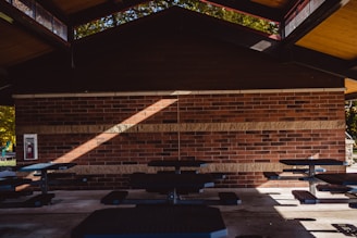A shaded area with picnic tables and a grill under a pergola.