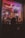 A dimly lit storefront window display features a large toy soldier surrounded by smaller toy soldiers. Neon lights in pink and purple cast a glow, with a sign overhead. The silhouette of a person looking into the window creates a mysterious vibe.