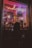 A dimly lit storefront window display features a large toy soldier surrounded by smaller toy soldiers. Neon lights in pink and purple cast a glow, with a sign overhead. The silhouette of a person looking into the window creates a mysterious vibe.