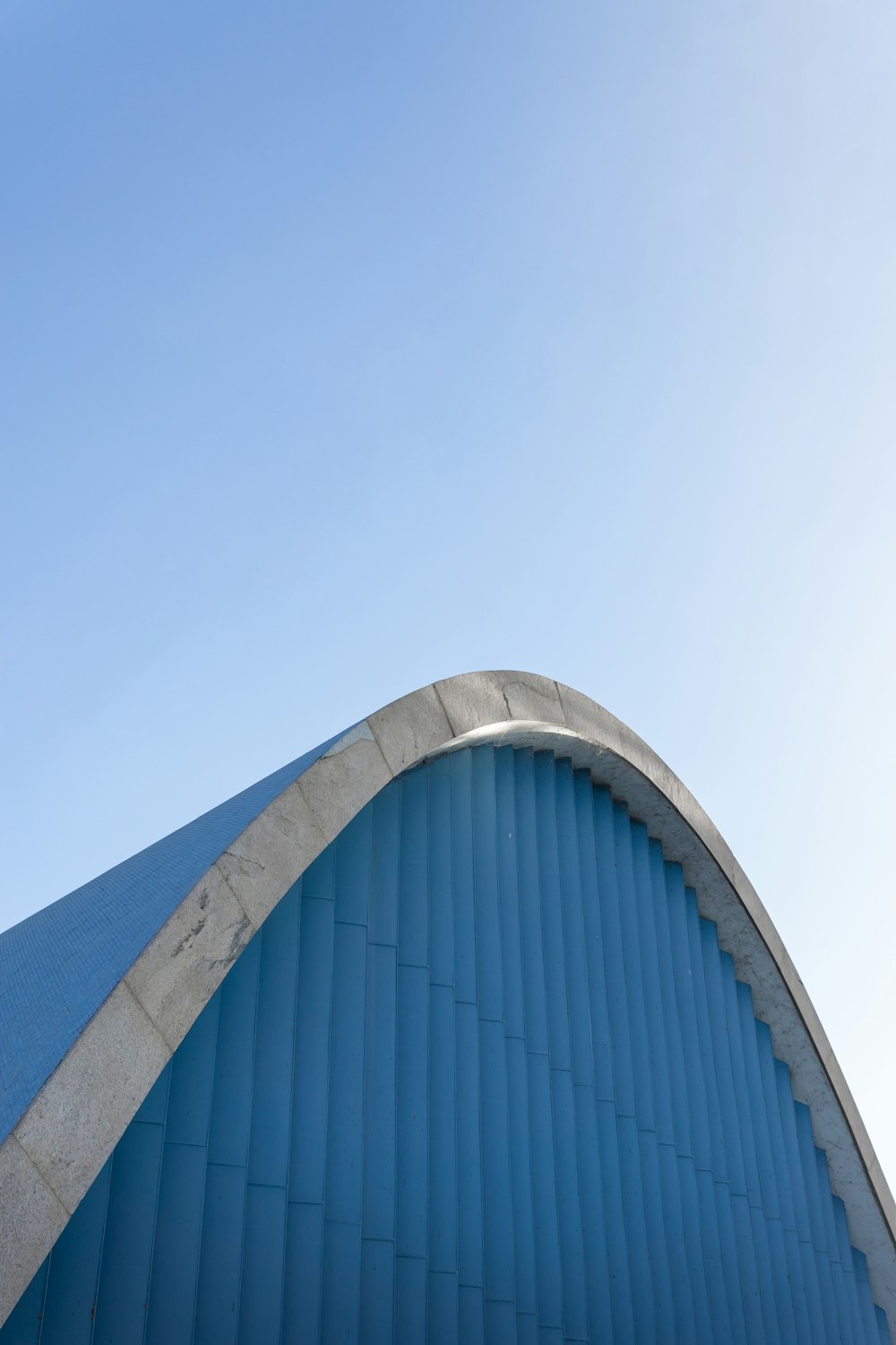 a blue building with a curved roof and a sky background
