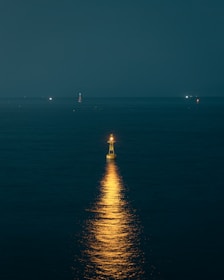 A warm glowing lighthouse shining over a calm sea at dusk, symbolizing guidance.