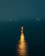 A serene lighthouse glowing warmly against a dark, stormy sea at night.
