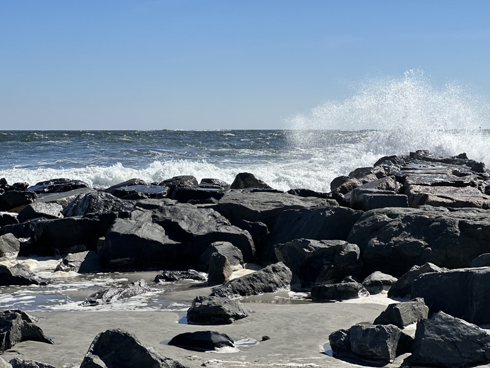 eine Person, die an einem felsigen Strand neben dem Meer steht