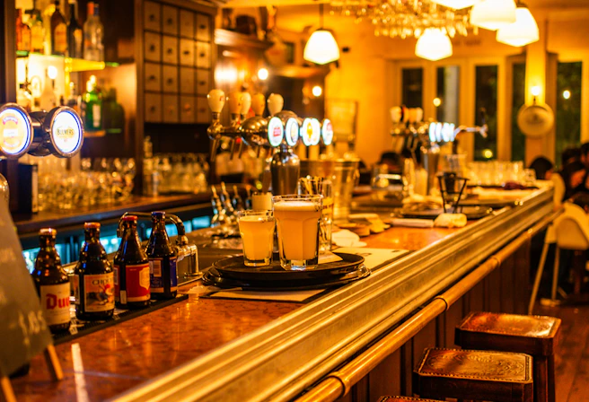 A warmly lit bar counter with an array of colorful cocktail tools and fresh ingredients laid out invitingly.