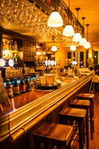 A cozy bar counter with warm lighting and a friendly bartender ready to assist customers.