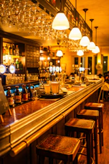 A stylish bar counter with a bartender mixing cocktails surrounded by warm lighting.