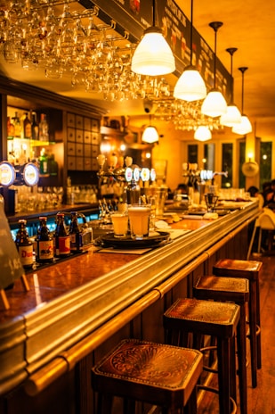 A warmly lit bar setup featuring elegant glassware and a polished wooden counter.