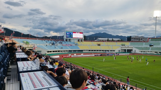 A lively soccer match in progress on a sunny day at a local Bizkaia field, with enthusiastic fans cheering.