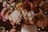 A vibrant arrangement of diverse flowers in rich, earthy tones, including dahlias and chrysanthemums, is elegantly displayed in a soft-focus setting. The interplay of natural colors is complemented by delicate string lights interwoven among the floral arrangement.
